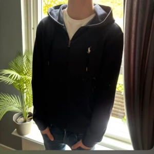 Zip Hoodie från Polo Ralph Lauren - Skön och stilren zip Hoodie från Polo Ralph Lauren. Modellen är Performance och i Marinblå färg. Storlek S. Tröjan är i mycket Gott skick och perfekt till en bekväm men uppklädd Look!🤞