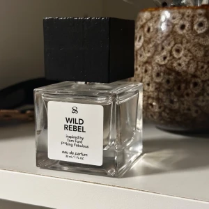 Wild Rebel Eau de Parfum - En modern parfym inspirerad av Tom Ford F*cking Fabulous. Kommer i en stilren flaska med 30 ml volym. Perfekt för dig som vill sticka ut och visa din personlighet.