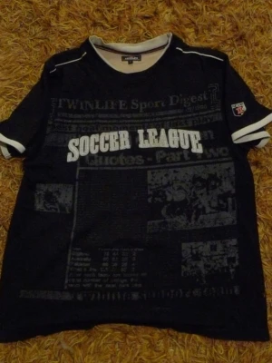 Svart t-shirt Soccer League Twinlife - Cool svart t-shirt från Twinlife med trycket 'Soccer League' i vitt på bröstet och sportiga detaljer. T-shirten har korta ärmar med vita ränder och grafiskt mönster framtill. Pris kan diskuteras😇😇