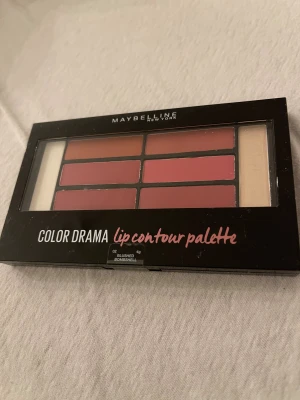 Maybelline Color Drama Lip Palette - Säljer en Maybelline Color Drama lip contour palette i färgen Blushed Bombshell. Paletten innehåller flera nyanser av rosa och nude för läpparna, perfekt för att skapa olika looks. Kommer i en smidig svart förpackning med genomskinligt lock.