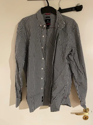 Svartvit rutig skjorta från Victorinox - Snygg svartvit rutig skjorta från Victorinox i tailored fit. Skjortan har klassisk krage, långa ärmar och knäppning framtill. Tillverkad i en mix av bomull, nylon och lycra för en bekväm känsla och bra passform. Perfekt för dig som gillar stilrena mönster.