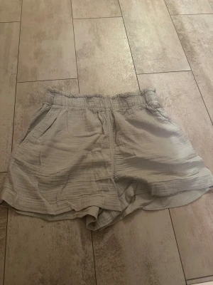 Beige shorts från H&M i bomull - Säljer ett par ljusbeige shorts från H&M i storlek S. De har en skön loose passform, resår i midjan och är gjorda i mjuk bomull med lätt struktur. Perfekta för varma dagar och chill häng. Två sidofickor för mobilen eller nycklar.