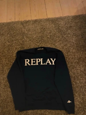 Mörkblå sweatshirt från Replay - Mörkblå långärmad sweatshirt från Replay med stor vit logotyp på bröstet. Tröjan har rund hals och ribbade muddar vid ärmslut och nederkant. Perfekt för dig som gillar stilrena och enkla plagg med tydlig branding. (Använd 5-10 ggr) så typ helt ny