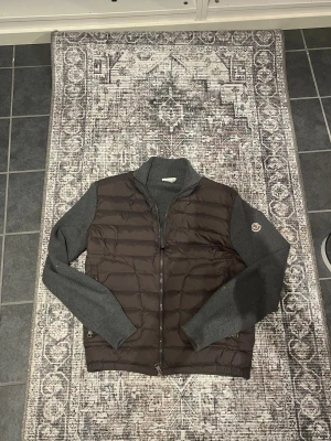 Moncler grå och brun pufferjacka - Snygg cardigan från Moncler med quiltad mörk grå front och lite ljusare grå stickade ärmar och rygg. Säljer då den börjar bli lite liten, passar mellan 172-181. Extremt bra skick och ser helt ny ut! Priset är ej hugget i sten🤩                                                         (vågar inte svara på om den är äkta eller ej därav priset) 