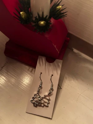 silver jul örhängen - Säljer ett par silvriga örhängen i form av julgranar, perfekt till jul!!