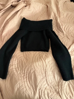Svart offshoulder stickad tröja - Snygg svart stickad tröja med croppad passform och bred offshoulder-krage.