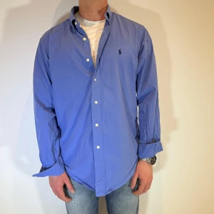 Blå Ralph Lauren skjorta  - Blåa Ralph lauren skjorta || Storlek M (Classic Fit) || Skjortan är i bra skick, däremot urtvättad och Normalt slitage förekommer || Modellen är 170cm och väger 63kg || Tveka inte på att höra av dig vid frågor eller funderingar 