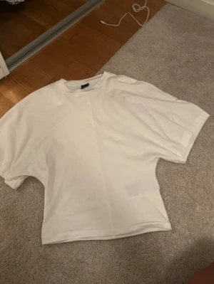 Vit oversized t-shirt - Säljer en vit oversized t-shirt med rund hals och korta ärmar. Enkel och clean design, perfekt att styla med jeans eller shorts. Materialet känns mjukt och bekvämt mot huden. Passar dig som gillar en loose fit och minimalistisk look.