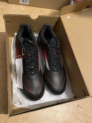 Adidas F50 Svarta/Röda  - Svart/Röda F50 Turf Grus underlag används till grus och konstgräs 