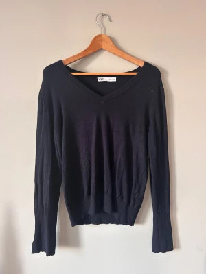 Svart v-ringad stickad tröja från Zara - Svart stickad tröja från Zara med v-ringad hals och långa ärmar. Tröjan har ribbade muddar med slitsdetalj vid ärmsluten och en klassisk, lite loose passform. Perfekt för dig som gillar enkel och stilren look.
