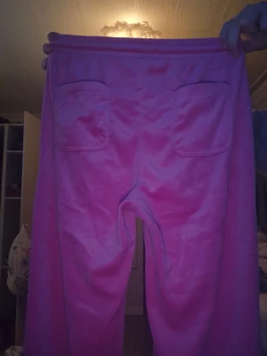 Rosa mjukisbyxor med snörning - Rosa mjukisbyxor med snörning i midjan och stora fickor både fram och bak. Byxorna är i ett mjukt material och har en relaxed passform, perfekta för chill dagar. Snygg och enkel design som är lätt att matcha med en hoodie eller t-shirt. Har ett litet hål i mellanbenen men det går jätte lätt att sy igen 