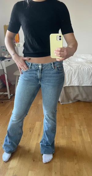 snygga ljusblå jeans  - Säljer ett par ljusblå bootcut jeans från Junkyard med klassisk femficksdesign och snygga sömmar på bakfickorna. Jeansen har låg midja och är tillverkade i mjukt denimtyg. 