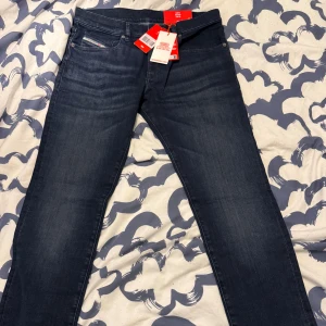 Diesel 2019 D-Strukt - OGRDJ jeans midwaist slim - Mörkblå jeans från Diesel, modell 2019 D-Strukt med slim fit och midwaist. Klassisk femficksdesign, snygga detaljer med Diesel-logga på bakfickan och patch i orange. Jeansen är tillverkade i stretchig denim för en bekväm passform. Nypris 1300 kr, priset är inte hugget i sten! Jeansen är aldrig använda