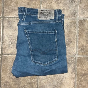 Replay Anbass jeans  - Snygga Replay Anbass jeans i klassisk blå färg med slim fit passform. Jeansen har fem fickor, tydliga sömmar och ett Replay-märke bak i midjan. Längd 104cm, midja 44cm. OBS de lagning i grenen/gylfen på sista bilden! JAG SKICKAR EJ FLER BILDER NÄR JAG BÄR JEANSEN! för storleksguide hänvisar jag till måtten och för bättre inblick i passformen rekommenderar jag att googla på modellnamnet. :) S4