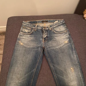 Nudie Jeans Bootcut Ola 30/32 blå - Bootcut jeans från Nudie Jeans i modellen Bootcut Ola. Färgade i klassisk mellanblå denim med slitningar och snygga kontrastsömmar. Bakfickorna har Nudies ikoniska broderi i orange. Tillverkade i 100% bomull för en autentisk jeanskänsla.