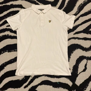 Helt ny Lyle scott piké  - Vit pikétröja från Lyle & Scott Junior med klassisk krage och tre knappar framtill. På bröstet sitter en logga. Helt ny!