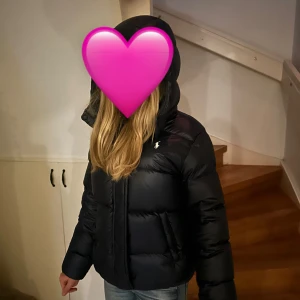 Blå pufferjacka från Polo Ralph Lauren - (Jackan är helt oanvänd !) i jackan står det 12-14 men passar även mig som är 160 🩷! Snygg mörkblå vinterjacka från Polo Ralph Lauren med huva och vitt broderat logomärke på bröstet. Jackan har dragkedja framtill och två sidofickor. Tillverkad i syntetmaterial, perfekt för kalla dagar. Köpte jackan i butik så minns inte vad den kosta men hittade en lika dan med rött Ralph lauren märke för 3060 men jag säljer den för 2000🙏🩷