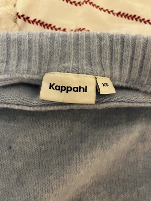 Ljusblå stickad tröja från Kappahl - Supermysig ljusblå stickad tröja från Kappahl i storlek XS. Tröjan har ribbade detaljer vid hals, ärmslut och nederkant samt en lite boxig passform med slitsar i sidorna. Perfekt för lager-på-lager under kyliga dagar.