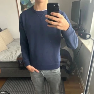 Mörkblå sweatshirt från Polo Ralph Lauren - Säljer en stilren mörkblå sweatshirt från Polo Ralph Lauren. Tröjan har rund hals, långa ärmar och ribbade muddar vid ärmslut och nederkant. Perfekt för dig som gillar enkel och klassisk design. Materialet är mjuk bomull för skön komfort.