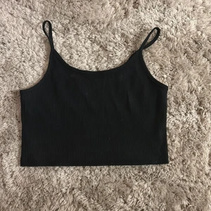 Svart ribbad linnetopp - En svart croppad linnetopp med smala axelband och ribbad struktur. Storlek XS, lite använd men passar inte längre. Pris kan diskuteras 🥰