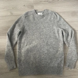 Grå stickad tröja från Selected Homme - Mjuk och stilren grå stickad tröja från Selected Homme i storlek M. Rund halsringning och ribbade muddar vid ärmslut och nederkant. Perfekt för dig som gillar enkel och clean look, oanvänd. Skicka för mer bilder eller vad som
