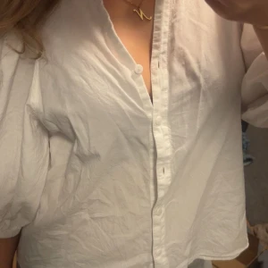 Vit skjorta med puffärm och knappar - Säljer en vit skjorta med puffiga trekvartsärmar och knappar framtill. Skjortan har en avslappnad passform och är tillverkad i ett lätt bomullstyg. Perfekt för dig som gillar en clean och stilren look.