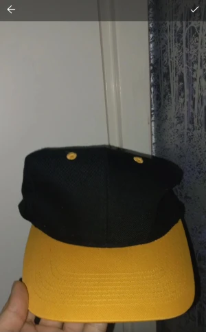 Svart och gul keps med böjd skärm - Snygg keps i svart med gul böjd skärm och matchande gula detaljer på ovansidan. Klassisk modell som passar perfekt till streetwear och chill vardagsstil. Tillverkad i slitstark bomull som andas bra. Enkel och stilren design som sticker ut med färgkombon.