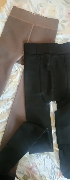 Fodrade leggings i svart och brunt - Två par fleecefodrade leggings, ett par svarta och ett par bruna. Båda är högmidjade och har en tight passform. Perfekta för kalla dagar med mjukt och varmt innerfoder. Snygga att bära till oversized tröjor eller hoodies. En för 120kr två st. För 200kr.