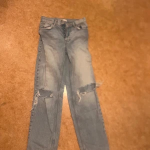 Ljusa ripped jeans från g perfect jeans - Säljer ett par ljusblå jeans från g perfect jeans i storlek 32. De har snygga slitningar och hål vid knäna för en trendig, avslappnad look. Klassisk femficksmodell med knappstängning och dragkedja. Perfekt för dig som gillar streetstyle.