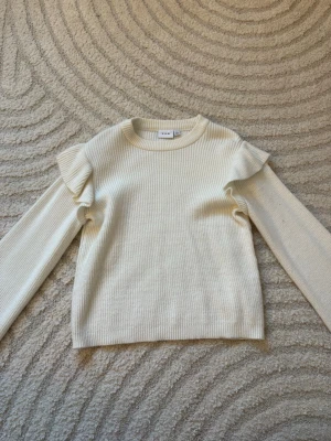 Vit stickad tröja med volang från Vila - Supersöt vit stickad tröja från Vila i storlek XS. Tröjan har rund hals, långa ärmar och snygga volangdetaljer vid axlarna som ger en extra touch. Ribbad struktur och mjukt material gör den både bekväm och stilren. Perfekt för dig som gillar enkel men trendig stil. Pris går att diskuteras!💓