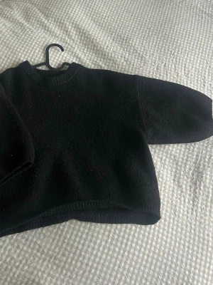 Svart stickad tröja från Gina Tricot - Mysig svart stickad tröja från Gina Tricot i storlek M. Tröjan har en klassisk rund halsringning och korta  ärmar. passar till både jeans och kjol.