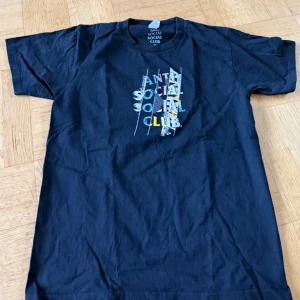 Svart t-shirt - Säljer en svart t-shirt med färggrafiskt tryck på både bröstet och ryggen. T-shirten har klassisk passform och korta ärmar. Materialet är mjuk bomull och trycket har en cool mix av olika färger och mönster. Obs! Rep! Därav priset. 