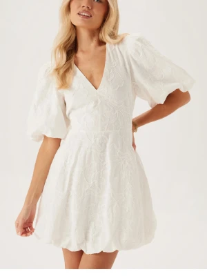 Vit kort klänning med puffärmar - Superfin vit kort klänning med v-ringning, puffiga ärmar och broderade blommor. Perfekt till studenten!🤍Helt ny och aldrig använd, storlek xxs men passar också Xs/S. Nypris 899