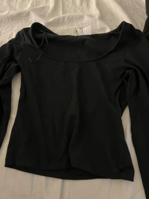 Svart långärmad topp från H&M - En svart långärmad topp från H&M med rundad halsringning. Toppen är i mjuk bomull och har en enkel, stilren design som passar till många olika outfits.