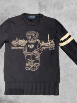 Mörkblå stickad tröja Polo Ralph Lauren - Nu säljs en blå stickad tröja med en björn och byggnader bakom björnen, nypris 1500