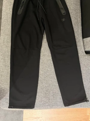 Svarta mjukisbyxor från Nike - Säljer ett par svarta mjukisbyxor, Nike tech fleece. Byxorna har raka ben och justerbara snören vid bensluten. Perfekta för chill eller träning. Storlek M, passar S