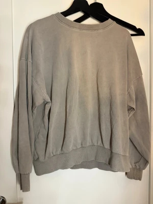 Beige oversized sweatshirt - En beige oversized sweatshirt med rund halsringning och ribbade muddar vid ärmslut och nederkant. Tillverkad i mjuk bomull, perfekt för en avslappnad och chill look. Passar dig som gillar enkel och stilren design.