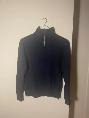 Marinblå quarter zip tröja Jack & Jones - Snygg marinblå långärmad tröja från Jack & Jones med half zip framtill. Tröjan har en hög krage och är tillverkad i mjuk bomull, perfekt för kyliga dagar. Enkel och stilren design som funkar till många olika outfits. Den är knappt använda och ganska lätt att töja ut.