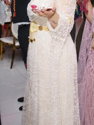 Vit kurdisk klänning - Säljer en vit långklänning med transparenta långärmar, täckt av pärlor och paljetter i ett glittrigt mönster. 