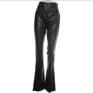 Svarta bootcut byxor i skinnimitation Zara - Snygga svarta byxor från Zara i skinnimitation med hög midja och bootcut-ben. Byxorna har en clean look utan synliga fickor eller detaljer, vilket ger en stilren vibe. Perfekta för dig som vill sticka ut med en edgy stil. Storlek L men sitter som en s/m. Då den är liten i storleken 
