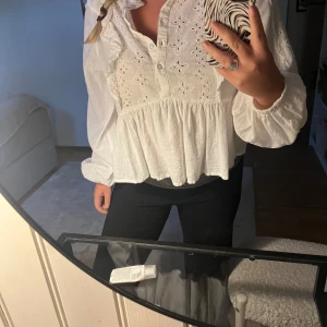 Vit blus med broderade detaljer BikBok - Superfin vit blus från BikBok med broderade blommönster och volangdetaljer längs axlarna. Blusen har knappar framtill, långärmade puffärmar. Andvänd endast en gång💖💖