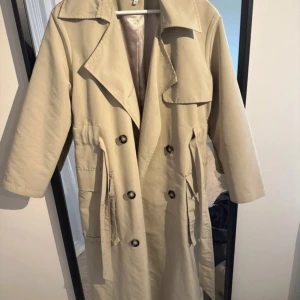Beige trenchcoat - 36 - Beige trenchcoat från NA-KD i storlek 36! Supersnygg med en oversized modell.
