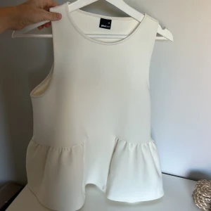 Vit volangtopp från Gina Tricot XS - Supersöt vit ärmlös topp från Gina Tricot i storlek XS. Älskar denna till jeans!