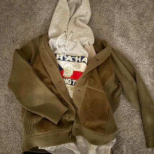 Soft brun kofta - Säljer en brun stickad kofta med knappar och en mocka detalj på framsidan. Riktigt snygg och skön till de kyligare dagarna. Storlek Large passar mig perfekt som är 185cm 85kg