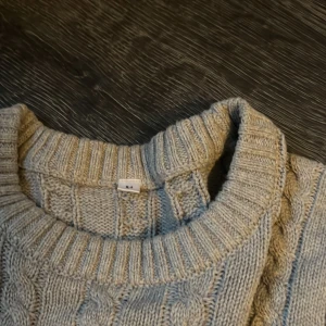 Grå kabelstickad tröja med rund hals - Säljer en grå kabelstickad tröja med rund hals och långa ärmar. Strl M! Skriv för frågor!