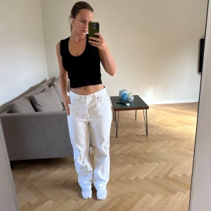 Vita raka jeans från TopShop - Säljer ett par klassiska vita jeans med rak passform och normal midja. Jeansen har fem fickor, knappgylf och är tillverkade i kraftig bomull. Perfekta för en clean och stilren look året runt. Saknar en knappt och har en liten fläck på ena benet.