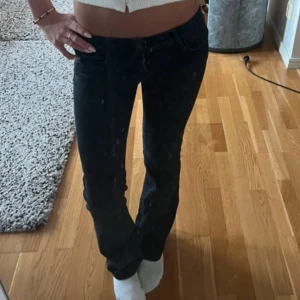 Lågmidjade jeans  - Säljer ett par svarta jeans med bootcut-modell och låg midja. Jeansen har klassisk femficksdesign och är i ett stretchigt denimtyg som sitter snyggt på kroppen. Perfekta för dig som gillar en tidlös och clean look.