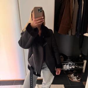 Svart teddyjacka från NA-KD med bälte - Säljer en svart teddyjacka/vinterjacka från NA-KD med bred krage, dragkedjor och bälte i midjan. Jackan har en oversized look och är fodrad med mjukt teddyfoder. 