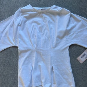 Vit t-shirt från Nelly i bomull - Säljer min super fina t-shirt/ blus från Nelly. Den är helt ny och har lappen kvar, säljer då den inte passa tyvärr🩷