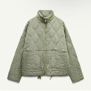 Quiltad grön jacka från Zara - Säljer denna gröna quiltade jacka från Zara i storlek M. Jackan har dragkedja framtill, två stora fickor och dragsko nertill. Den har en loose passform och är perfekt för höst och vår. Materialet känns mjukt och bekvämt, och den har en snygg, vågig quiltad design.